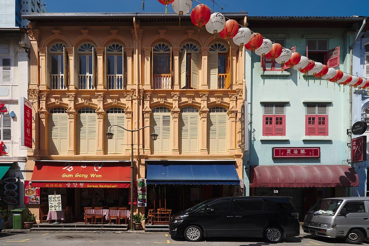 Restored shophouses with colourful shuttered windows and strings of lanterns in Chinatown, Singapore.